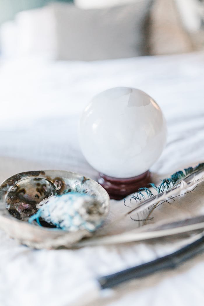 about-03 Crystal ball and feather with smudging tools on a soft surface, ideal for spiritual and mystical themes.